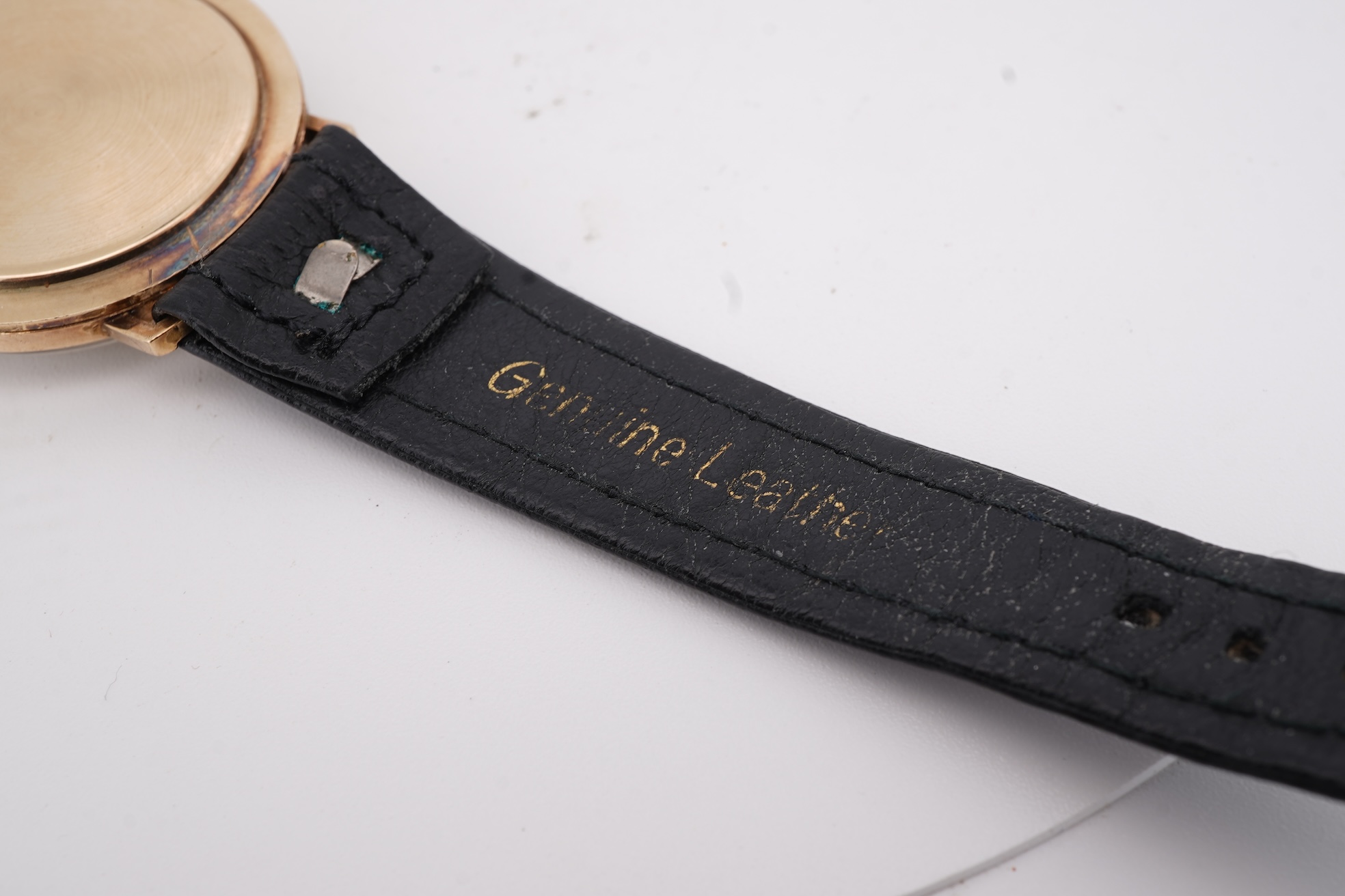 A gentleman's yellow metal Garrard manual wind wrist watch, with baton numerals and date aperture, case diameter 34mm, on a black leather strap.